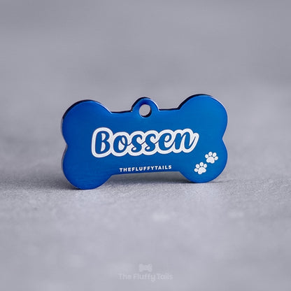 Hundbensformad namnbricka av rostfritt stål med högblank yta till hund, graverad med hundens namn i enkel kontur och två tassar.