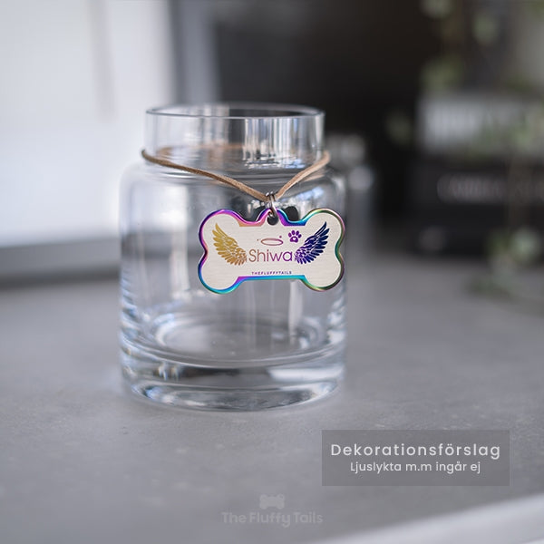 Hundbensformad minnesbricka i regnbågens olika färger hänger på en glasljuslykta. Graverad med vingar och husdjurets namn. Kan även användas som nyckelring.