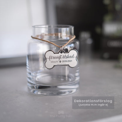 Silvrig hundbensformad nyckelring, minnesbricka med texten förevigt älskad, till minne av ett husdjur, hund eller katt som har gått bort. Hänger på en glasljuslykta.