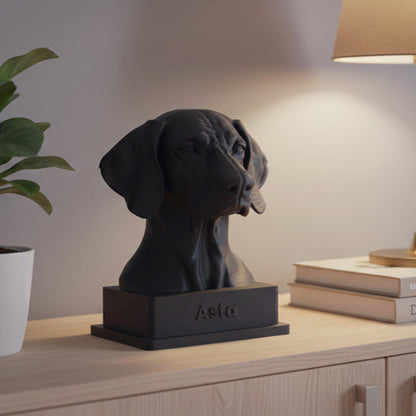 Interiörbild för inspiration med en svart hundskulptur i 3D av hundrasen weimaraner, inredd i minimalistiskt och skandinaviskt stil tillsammans med en vit kruka och grön växt, guldig bordslampa som står på två böcker
