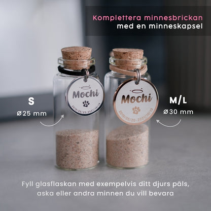 2 glasflaskor (minneskapslar) med runda minnesbrickor (en silver och en roséguld) på flaskhalsen