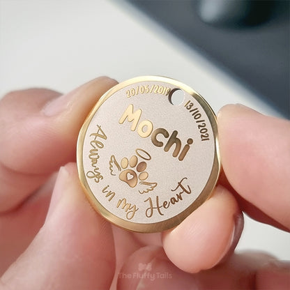 Rund, guldig nyckelring, minnesbricka med personlig gravyr av hundens namn och datum, tassavtryck med hjärta och vingar