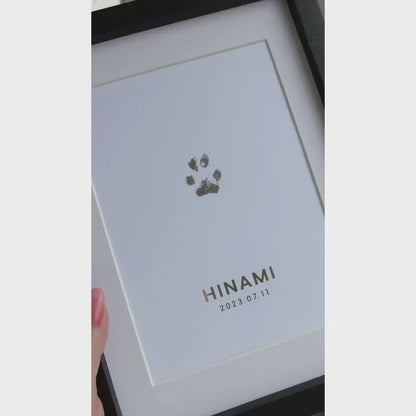 Video som visar en inramad TassPrint med tassavtryck folierat i silver. Tavlan vinklas i dagsljus för att visa foliens reflekterande effekt